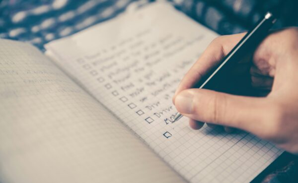 Photo of a hand and a check-list being written
